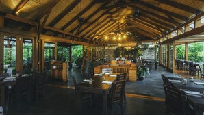 Un comedor amplio con mesas y sillas de madera, ventanas grandes y un techo alto con vigas a la vista.