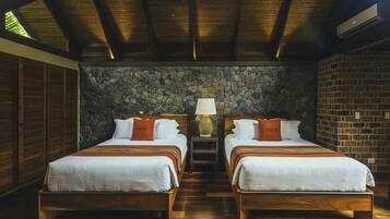 A hotel room with two wooden beds, a stone wall, and a wooden ceiling.