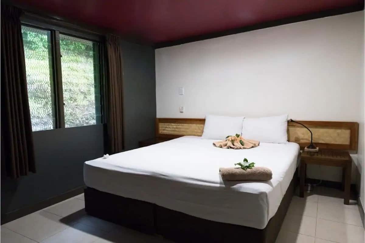 A neatly made bed with white linens, a wooden headboard, and a bedside table with a lamp.