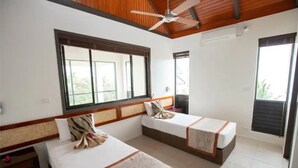 A hotel room with two beds, a ceiling fan, a large window, and a view of greenery outside. - Dreamview Villas - In Rakiraki (Rakiraki)