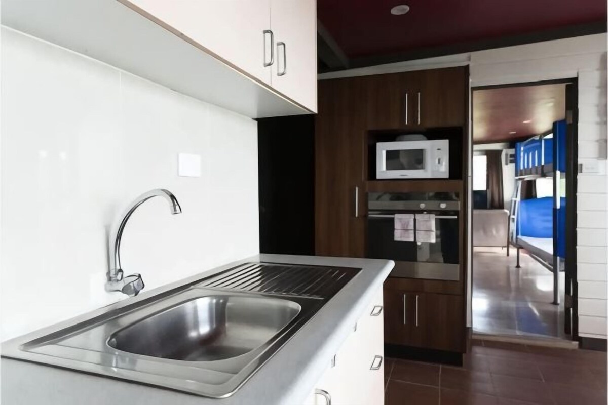 Una cocina moderna con electrodomésticos de acero inoxidable, microondas integrado y un lavamanos.
