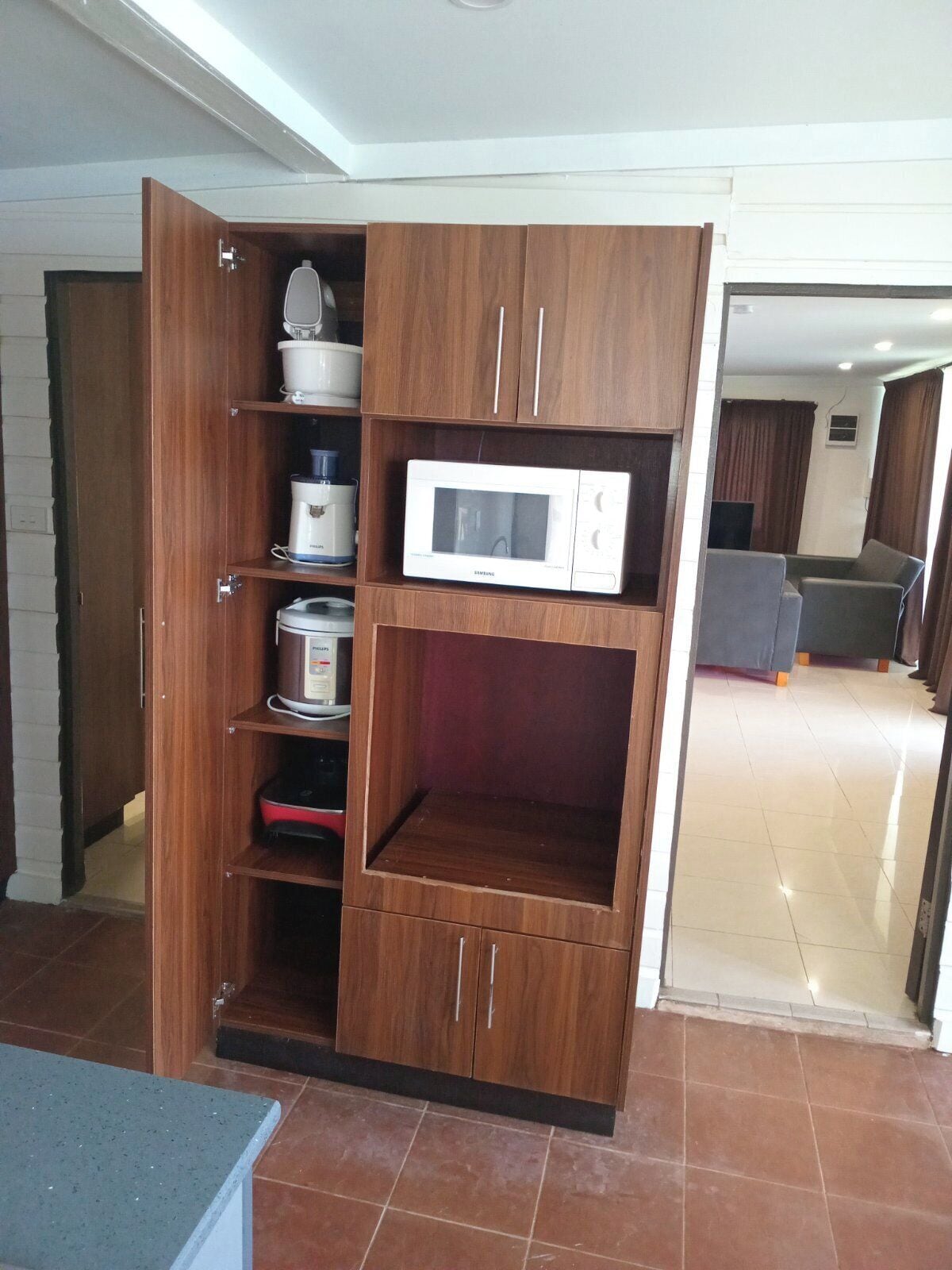 A kitchen with a built-in microwave, a coffee maker, and a rice cooker on open shelves.