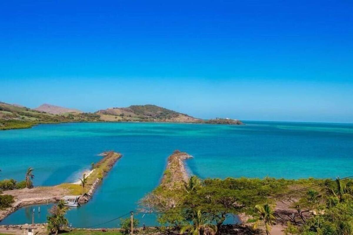 A coastal landscape with clear turquoise waters, a small boat dock, and lush greenery.