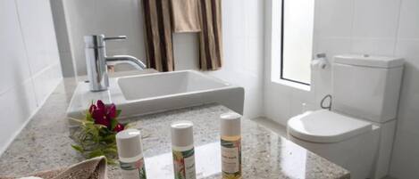 A bathroom with a granite countertop, a white sink, a toilet, and a towel rack with striped towels.