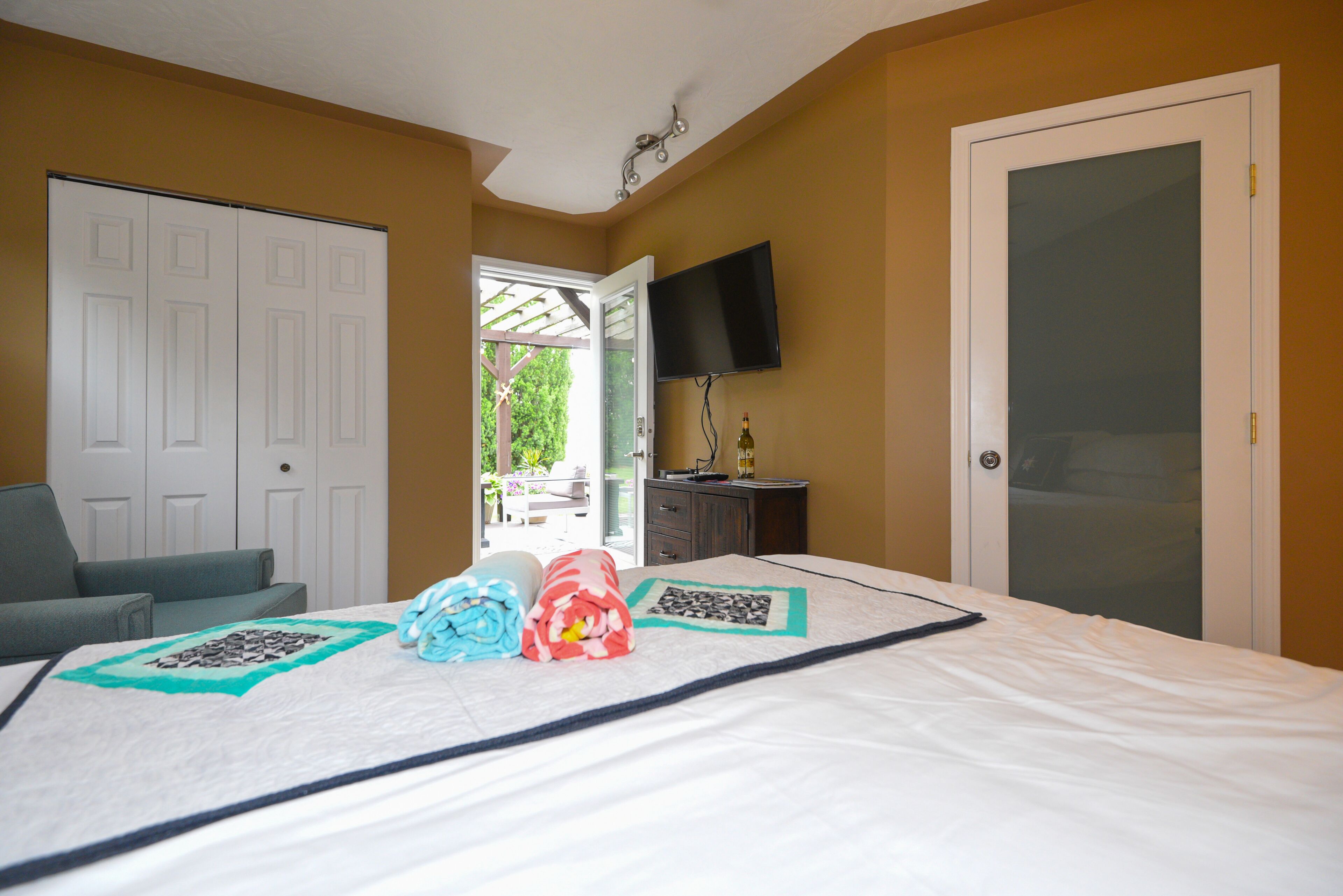 A hotel room with a bed, a TV mounted on the wall, a door, and a view of the outdoors.
