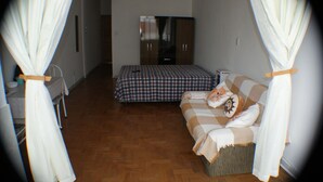 A bedroom with a bed, a sofa, and a wardrobe. - Apartamento Helvetia (São Paulo)