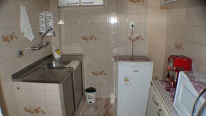 A compact kitchen with a sink, a small refrigerator, and a microwave. - Apartamento Helvetia (São Paulo)