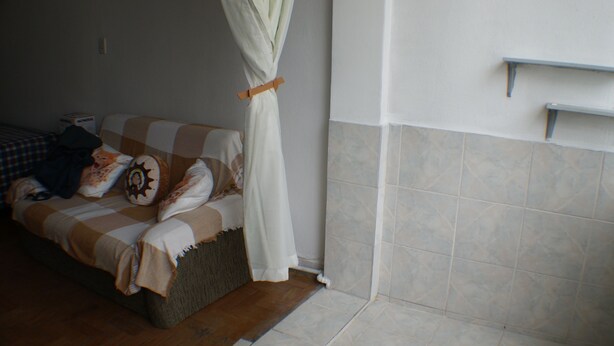 A bedroom with a bed, a bedside table, a nightstand, and a window with a curtain. - Apartamento Helvetia (São Paulo)