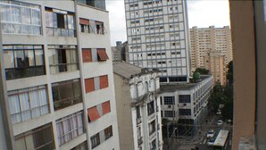 A multi-story building with a mix of architectural styles, including a section with large windows and another with smaller, more ornate details. - Apartamento Helvetia (São Paulo)