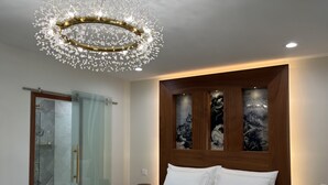 A bedroom with a bed, a shower, and a wall with artwork.