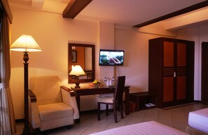 A hotel room with a desk, chair, television, wardrobe, and bed. - Pines Garden Resort (Prigen)