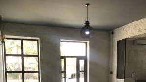 A spacious room with a large window, a leather sofa, and a hanging light fixture. - Hotel Aguna (Kutaisi)