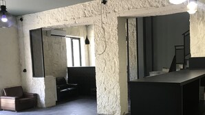 An open-plan living area with a kitchen island, a sofa, and a coffee table. There are hanging lights and a textured wall. - Hotel Aguna (Kutaisi)