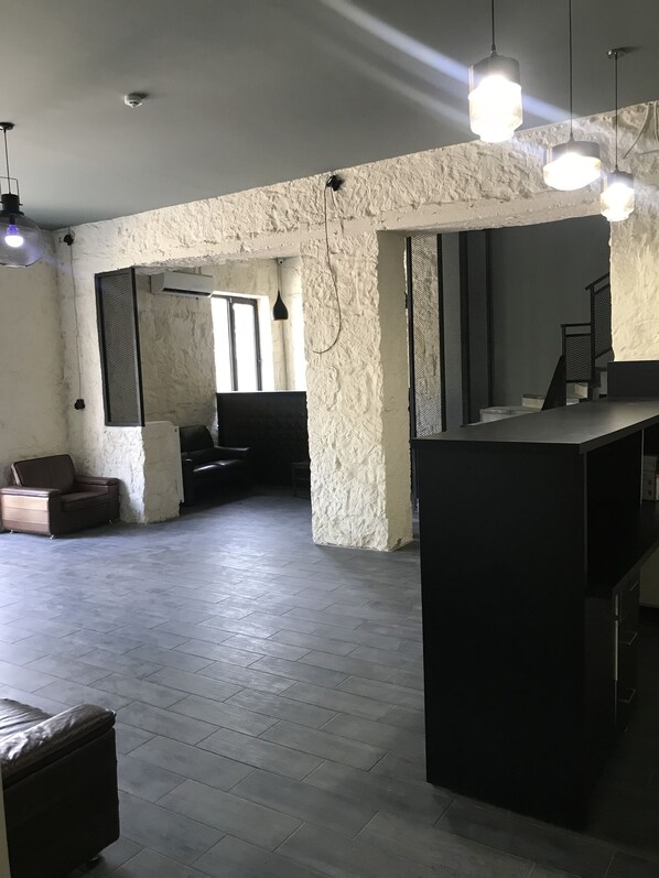 Un espacio habitable abierto con una isla de cocina, un sofá y una mesa de centro. Se observan luces colgantes y una pared con textura.