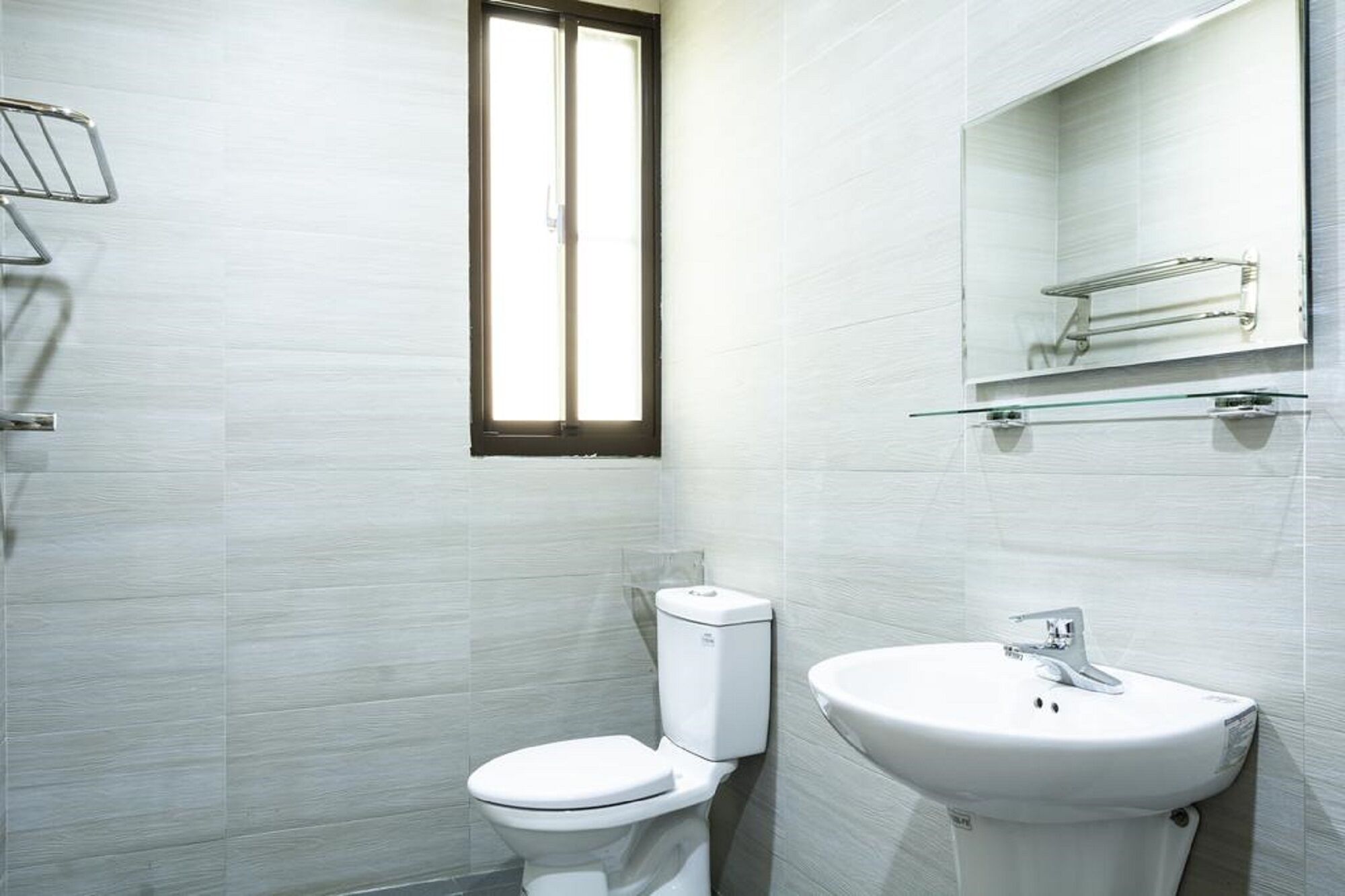 A modern bathroom with a toilet, sink, and a window.