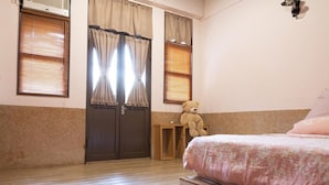 A bedroom with a bed, a wooden nightstand, a teddy bear, and a double door with curtains. - OAOA Anping House (Tainan)
