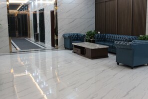 A lobby with a marble floor, a blue leather sofa set, and a small table with potted plants. - Yi Hao International Apartment (Guangzhou)