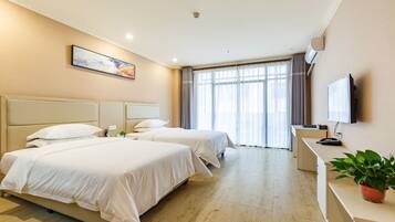 A hotel room with two beds, a desk, a TV, and a window with curtains.
