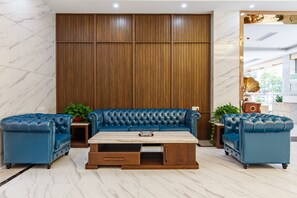 Un salon moderne avec un ensemble de canapés en cuir bleu, une table basse en bois et un sol en marbre.