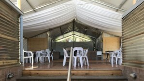 A covered outdoor area with steps leading up to a seating area with plastic chairs and tables. - Bushranger Hotel (Collector)