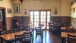 A restaurant with wooden tables and chairs, a brick wall, and a large window with natural light. - Bushranger Hotel (Collector)