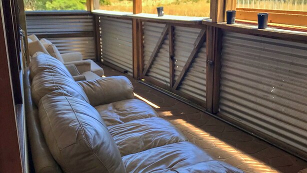 A room with a long, cushioned bench along the window, offering a view of a grassy landscape. - Bushranger Hotel (Collector)