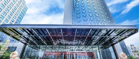 A modern building with a glass facade, a curved entrance, and two lion statues.