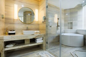 Ein modernes Badezimmer mit Marmorwaschtisch, einem runden Spiegel, einer freistehenden Badewanne und einer gläsernen Duschkabine.
