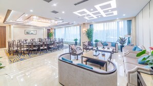 A spacious hotel lobby with a dining area, seating arrangements, and large windows. - Hundred Hotel (Qingdao)