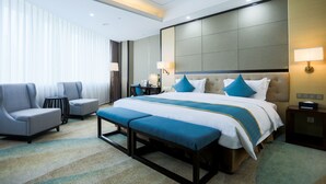 A hotel room with a large bed, a desk, two armchairs, and a small table. - Hundred Hotel (Qingdao)