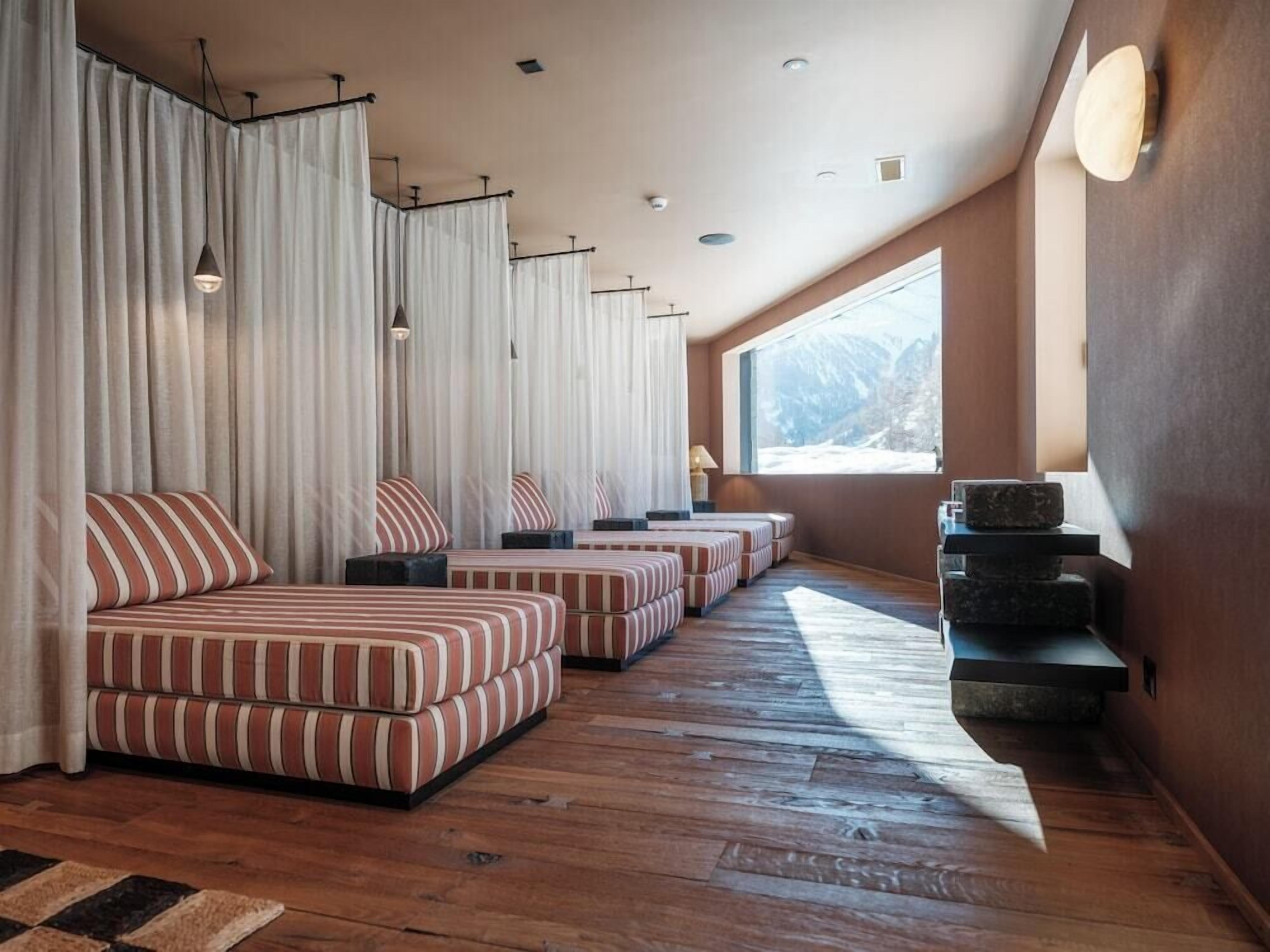 A modern room with striped sofas, a large window, and a wooden floor.