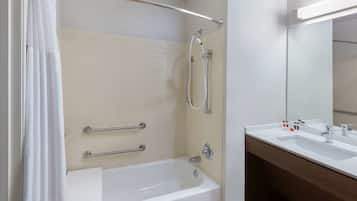 A modern bathroom with a bathtub, shower, and two sinks.