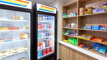 Eine Kühlvitrine mit verschiedenen Lebensmitteln sowie ein Regal voll mit Snacks und Getränken.