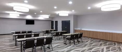 A conference room with tables and chairs, a podium, and a patterned carpet.