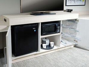 A kitchenette with a black refrigerator, a microwave, and a coffee machine.