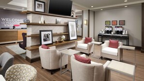 A modern lobby with seating areas, a reception desk, and a coffee station.