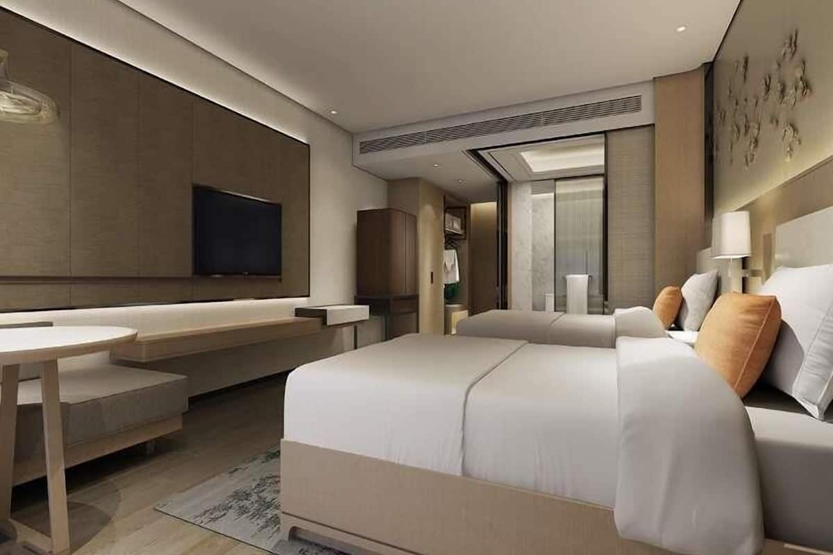 A modern hotel room with a large bed, a desk, and a television.