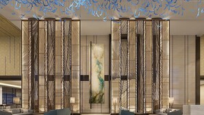 A modern lobby with a central art piece, a reception desk, and seating areas. - Howard Johnson Zhujiang Hotel Chongqing (Chongqing)