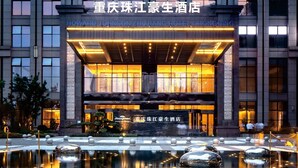 The exterior of the Howard Johnson Zhujiang Hotel Chongqing, featuring a modern facade, large windows, and a reflective water feature in front. - Howard Johnson Zhujiang Hotel Chongqing (Chongqing)