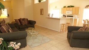 A living room with two sofas, a coffee table, and a kitchen area with a microwave and bar stools. - Ly53763 - Indian Ridge - 4 Bed 2 Baths Villa (Kissimmee)