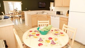 A compact kitchen with a dining area, wooden cabinets, a dishwasher, and a television mounted above the sink. - Ly53763 - Indian Ridge - 4 Bed 2 Baths Villa (Kissimmee)
