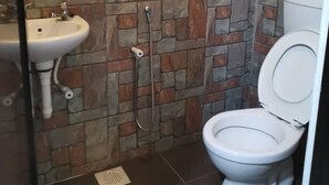 Un baño con pared de piedra, un lavabo, un inodoro y una ducha.