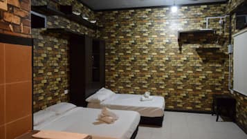 Een hotelkamer met twee bedden, een wastafel en een muur met bakstenen motief.
