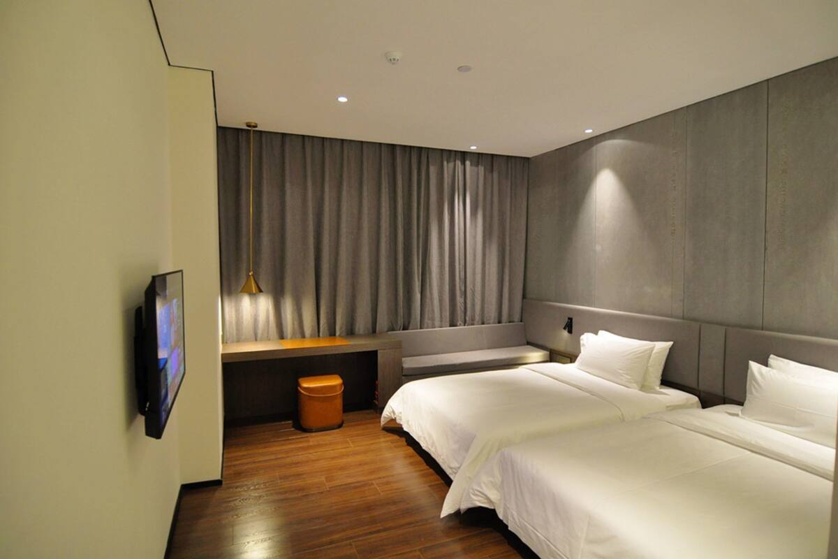 Ein modernes Hotelzimmer mit einem großen Bett, einem Schreibtisch und einem an der Wand befestigten Fernseher.