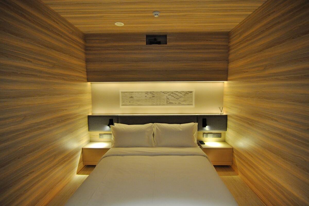 Ein modernes Schlafzimmer mit Holzboden, einem großen Bett, zwei Nachttischen mit Lampen und einem Wandbild.
