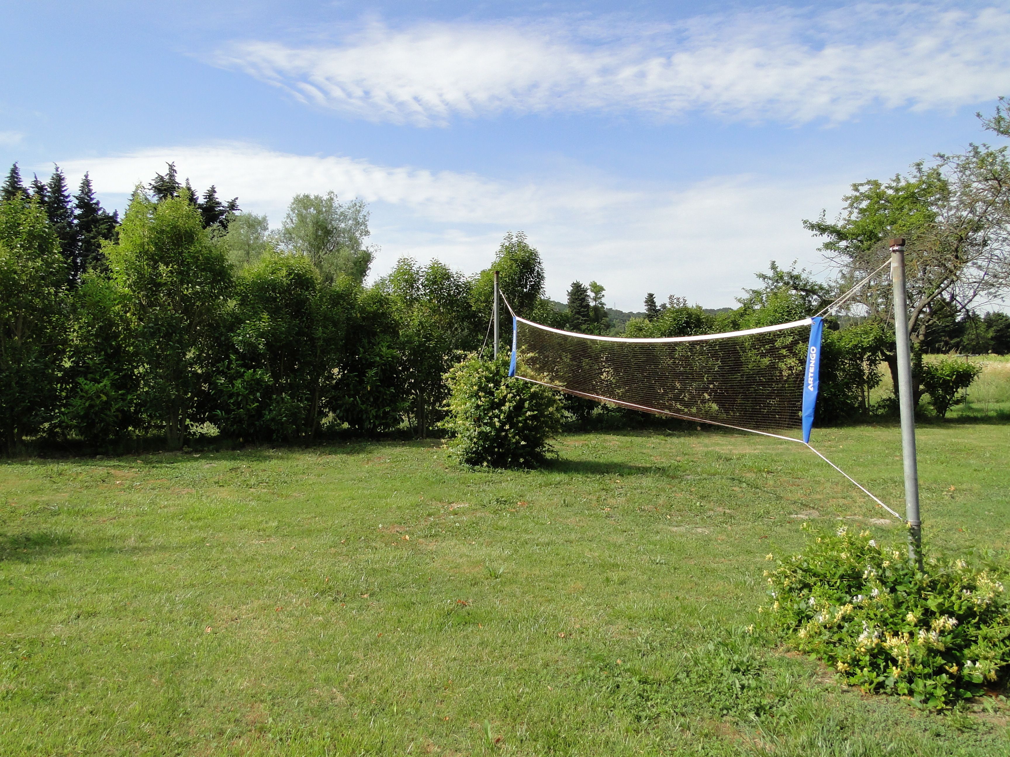 A netted area in a grassy field with trees in the background.