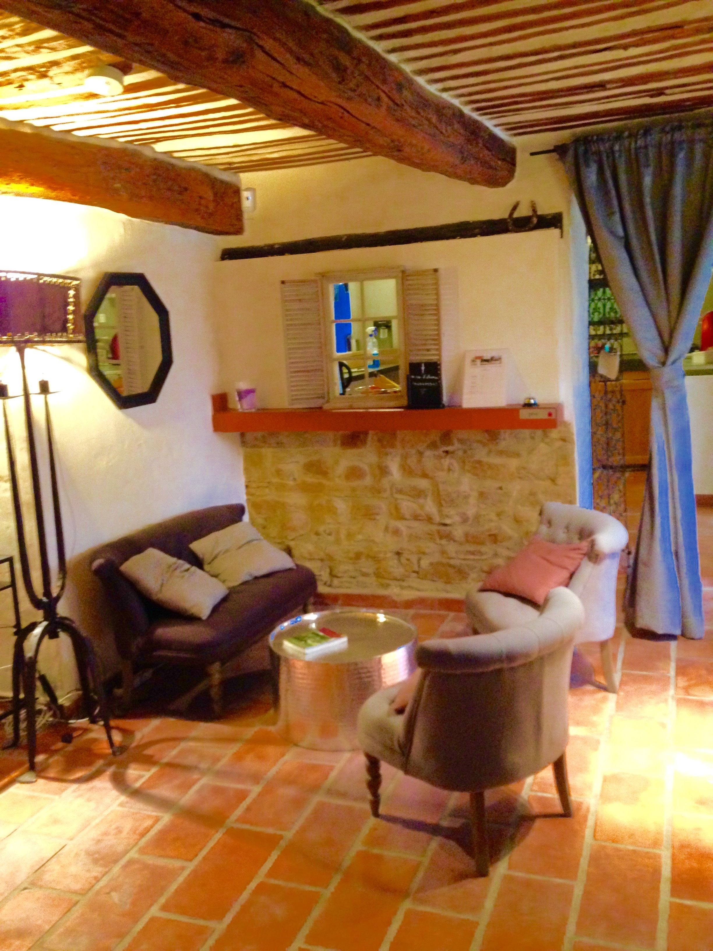 Un salon chaleureux avec un mur en pierre, un plafond en bois et un sol carrelé.