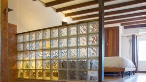 A bathroom with a bathtub, a wooden bench, and a glass partition wall. - Mas Julien (Orange)