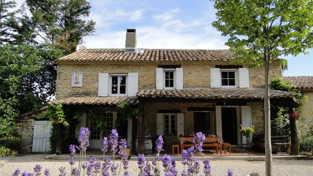 A stone house with a tiled roof, a covered porch, and a gravel driveway. - Mas Julien (Orange)