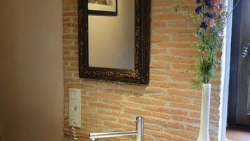 A bathroom with a white sink, a mirror, a vase with flowers, and a wooden countertop.